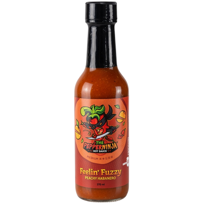A bottle of The Pepper Ninja Hot Sauce, 'Feelin' Fuzzy' Peachy Habanero flavor, featuring a red label with a cartoon ninja pepper illustration and a black cap, set against a plain white background.