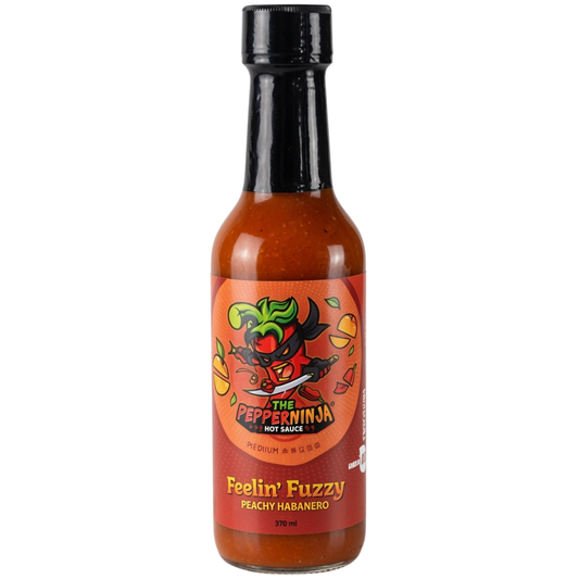 A bottle of The Pepper Ninja Hot Sauce, 'Feelin' Fuzzy' Peachy Habanero flavor, featuring a red label with a cartoon ninja pepper illustration and a black cap, set against a plain white background.
