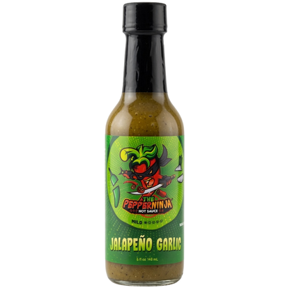A bottle of Pepper Ninja Mild Heat Jalapeño Garlic hot sauce on a plain white background. The bottle is filled with a greenish-brown sauce and features a black cap and a green cartoon label with a red pepper character.